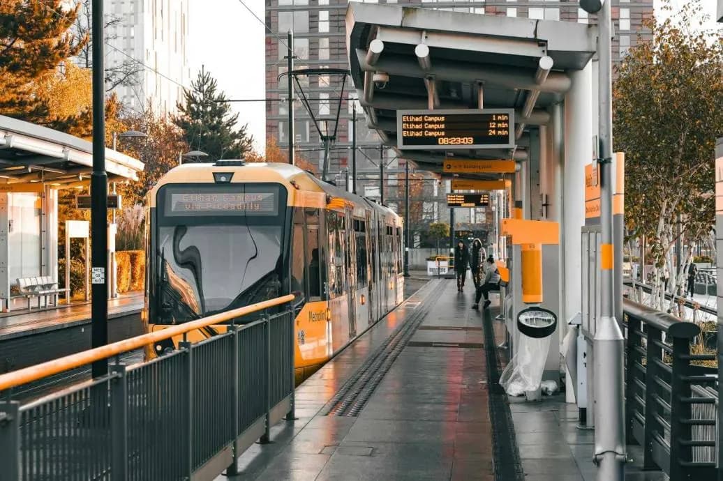 A yellow Manchester tram at a tram stop